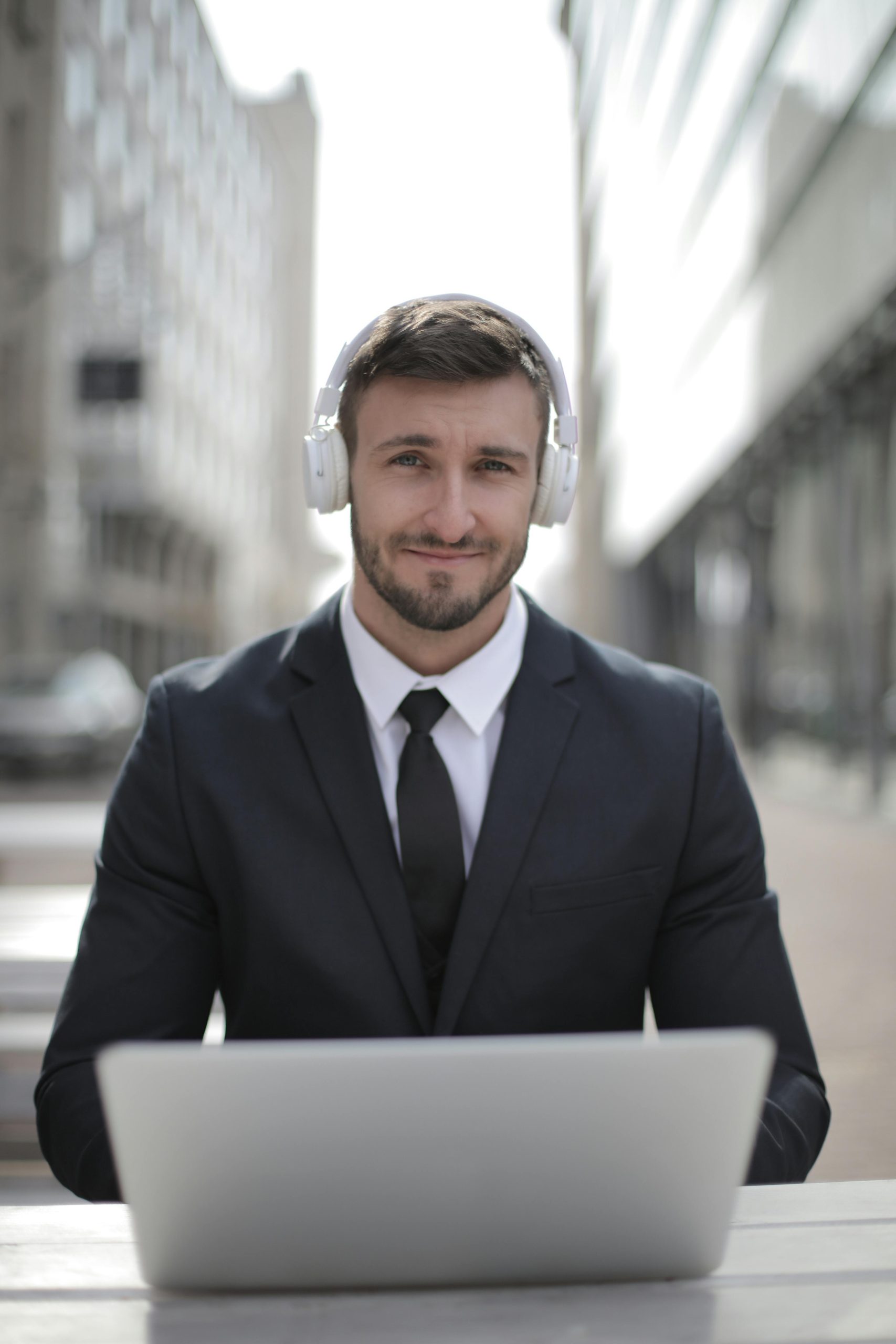 A smiling businessman in a suit using a laptop with headphones. Perfect for remote work and digital nomad themes.
